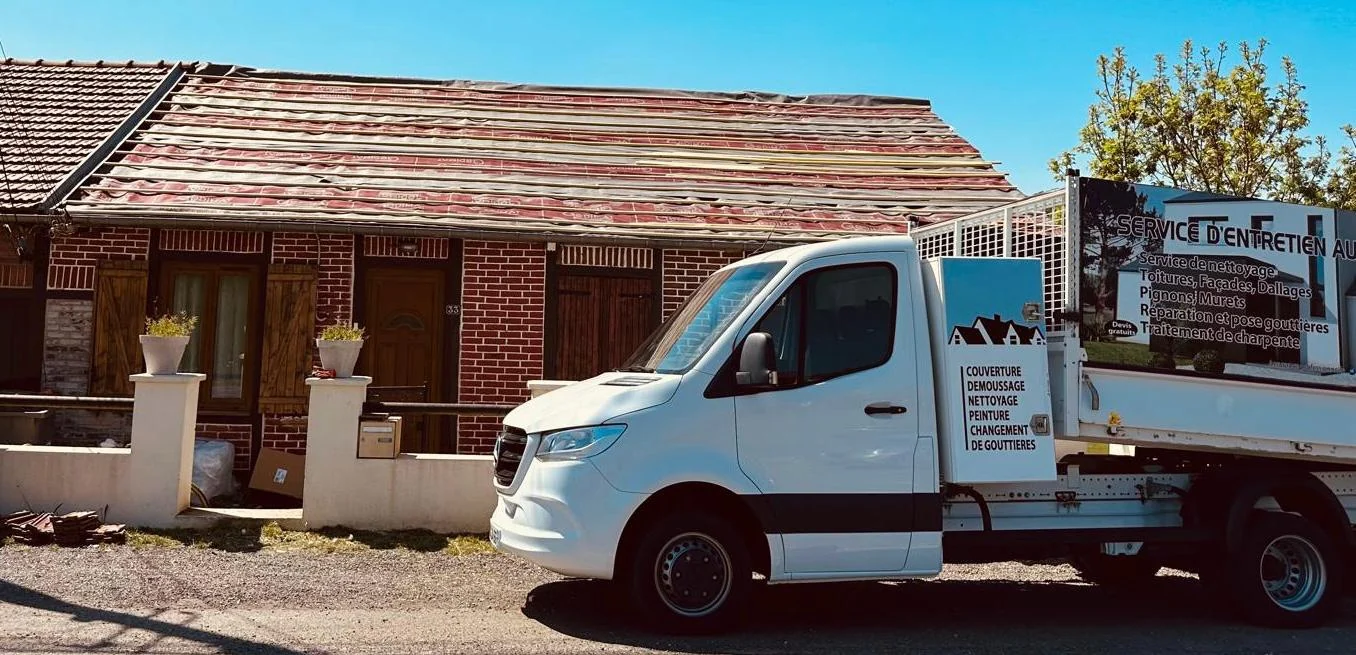 Dépose de l'ancienne couverture d'une maison, camion de l'entreprise stationné devant le chantier